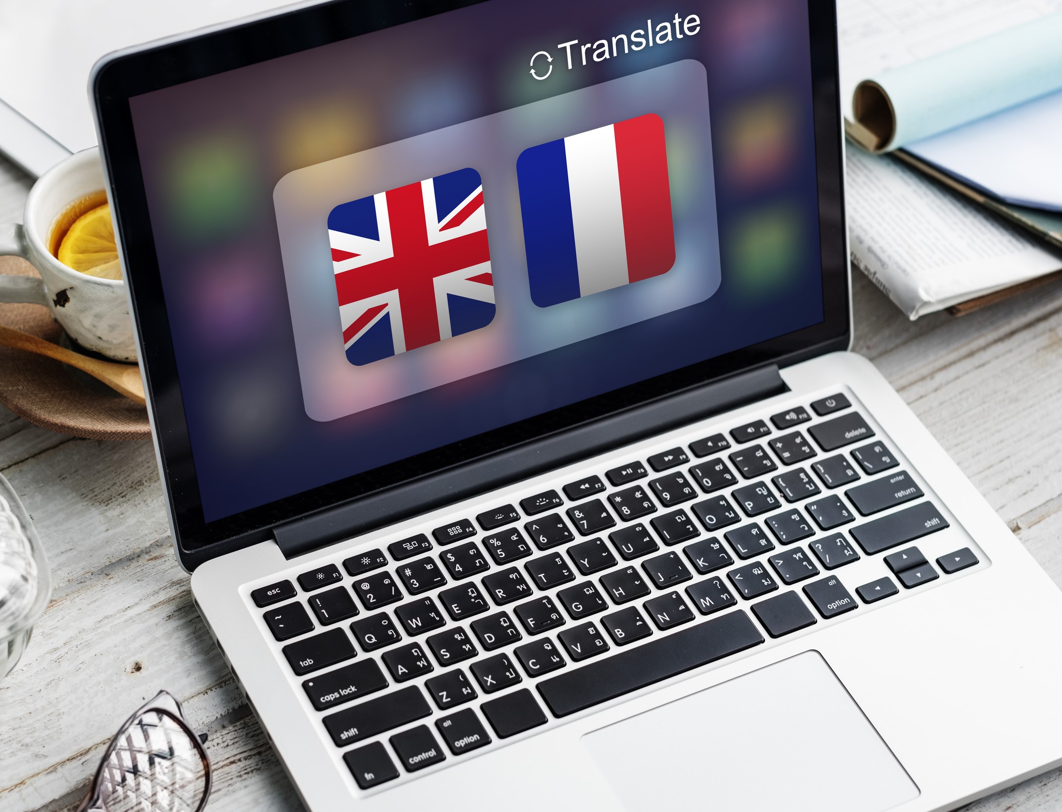 Grafika z komputerem otoczonym ikonami flag, ilustrująca różnicę między nakładkowym tłumaczeniem a pełnoprawnymi wersjami językowymi WordPress, które wymagają osobnych adresów URL i poprawnej struktury SEO.